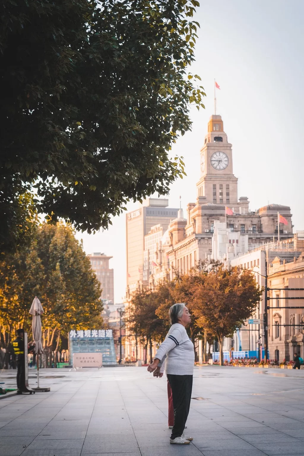 Een oudere vrouw doet rustige oefeningen buiten, passend bij balans, stabiliteit en actief blijven op latere leeftijd.